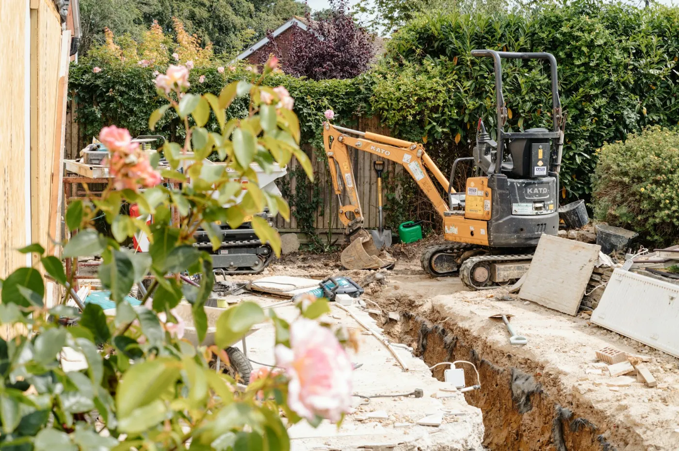 Minigrävare schaktar en dike i en villaträdgård